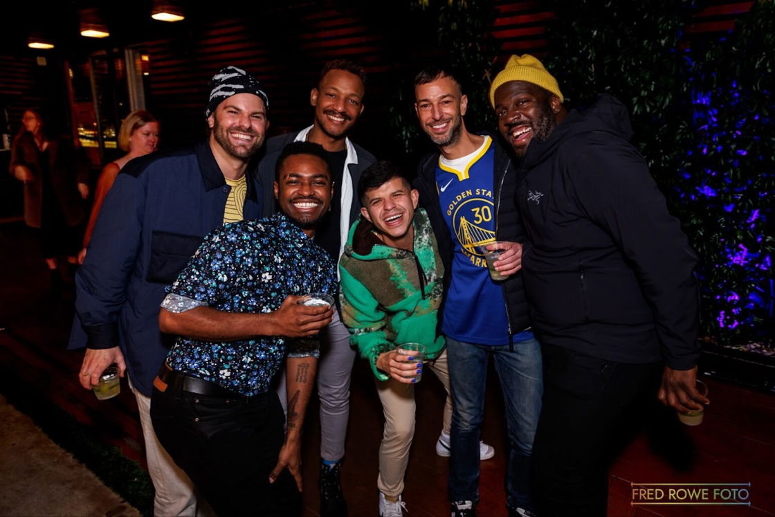 A group of men smile with their arms around each other at Phoenix Hotel's New Year's Eve Party in 2022.